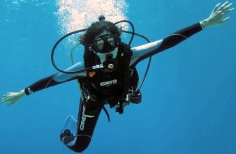 Diver floating with open arms facing the camera.