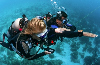 Two divers side by side navigating underwtaer using a compass and timer